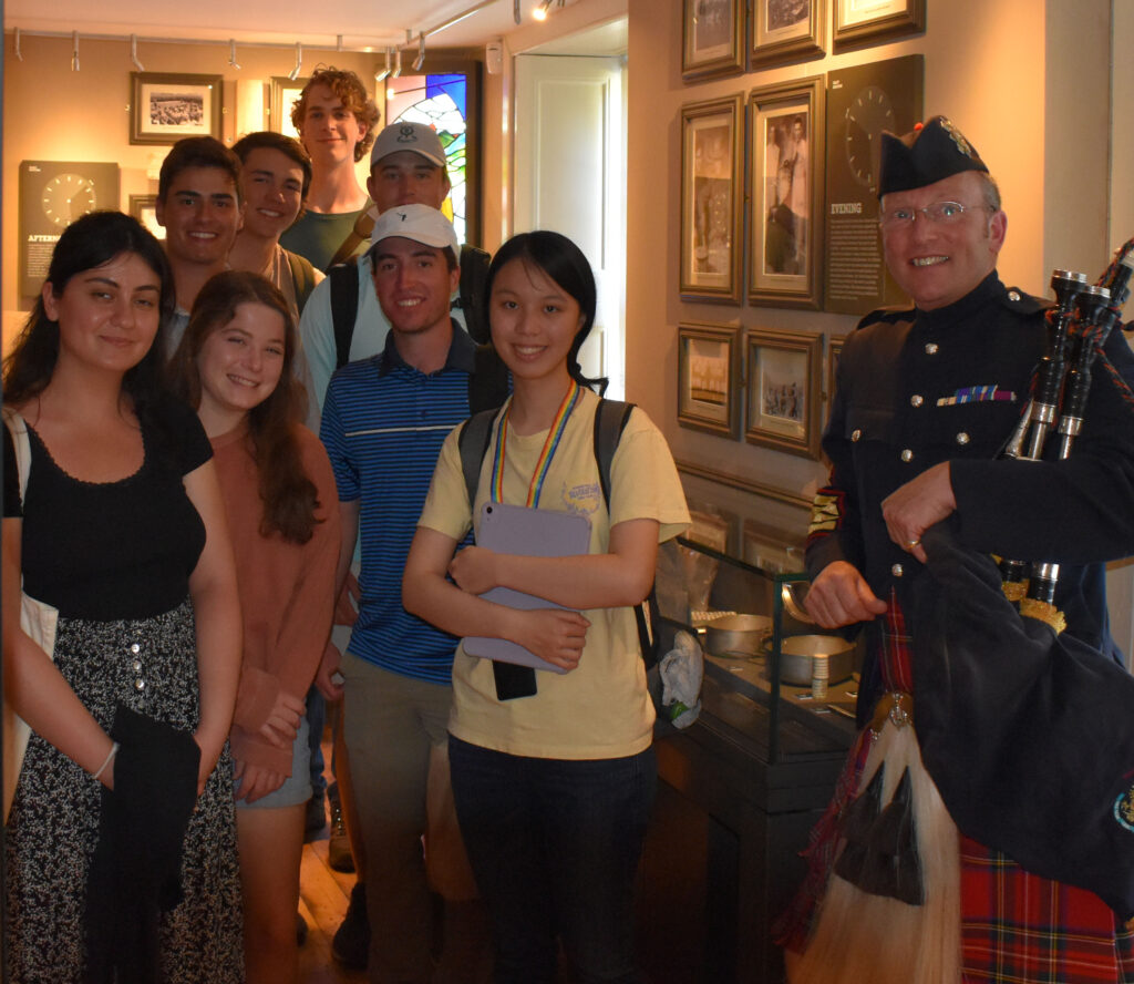 Group of people posing with a person holding a Bagpipe.