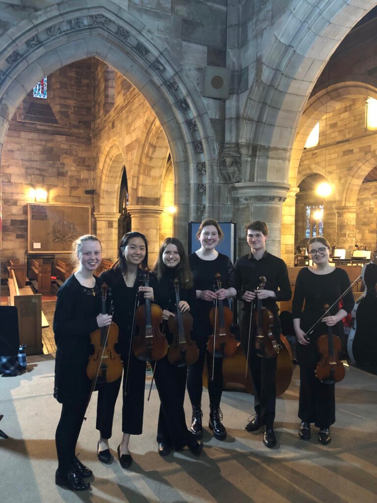 Group of people posing with their violas in a church.