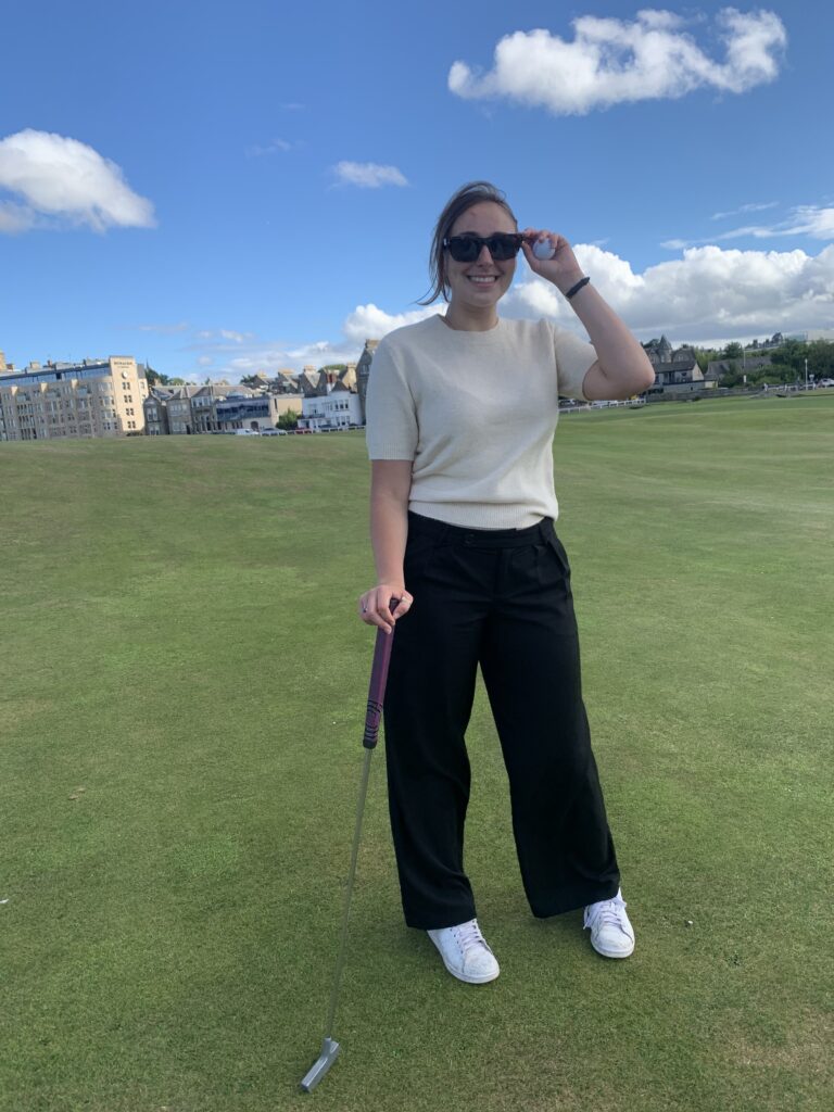 Lauren on the golf course holding a golf club and wearing sunglasses.