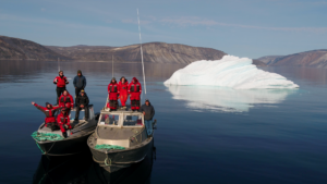 Group of researchers on two small boats, with ice floe and coastline in background