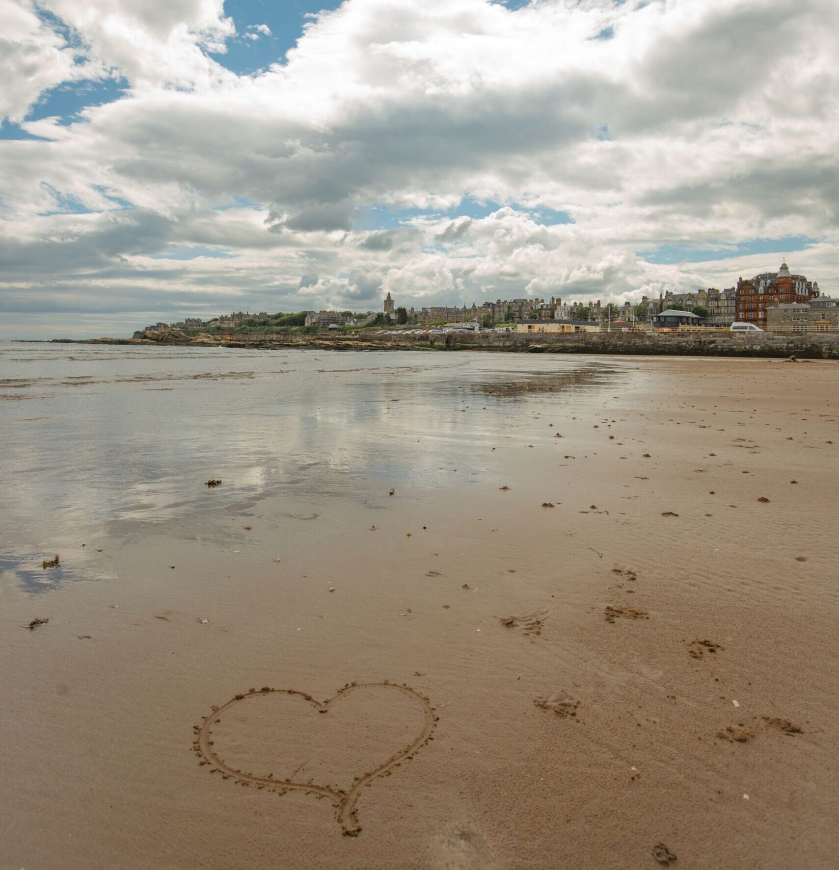 View of St Andrews from West Sands beach. A heart is drawn in the sand in the foreground.