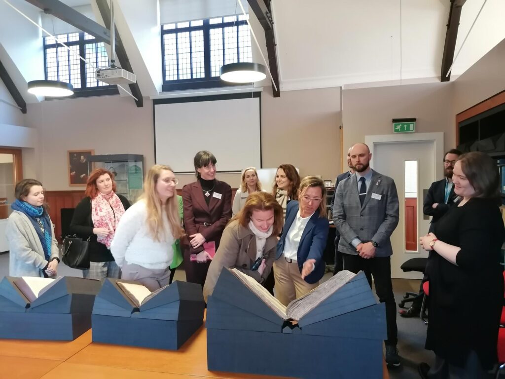 shared image A group of people viewing hsitoric manuscripts, in a Church-like building.